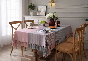 Close-up of houndstooth patchwork tablecloth featuring thick fringe details and soft tones