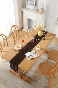 Close-up of black hollow lace table runner with elegant fringe details on wooden table