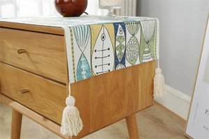 Close-up of Nordic style table runner with fish pattern and decorative cotton tassels