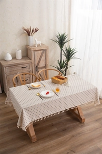 Detailed close-up of daisy print cotton tablecloth with elegant beige fringe accents