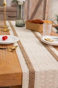 Close-up of woven linen table runner with tassels and diamond patterns on a wooden table