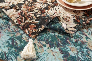 Macro detail of vintage floral jacquard tablecloth with elegant off-white fringe edges