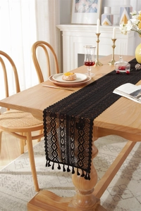 Detail of black crochet lace table runner with hollow design and elegant fringe tassels