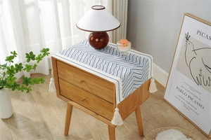 Close-up of blue and white zigzag knitted runner with elegant tassel detail for furniture