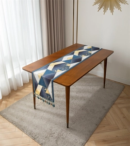 Detailed view of jacquard table runner with geometric gold patterns and tassel edges