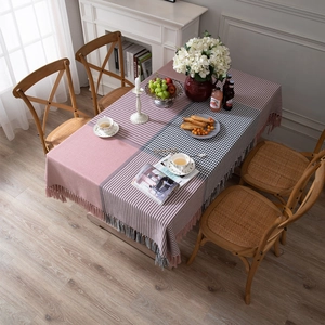 Modern thick pink and gray plaid tablecloth with tassels on a wooden dining table