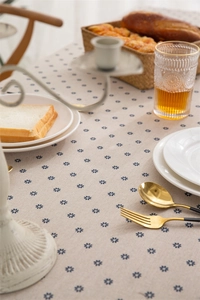 Detail of floral daisy pattern on beige cotton tablecloth with breakfast setting