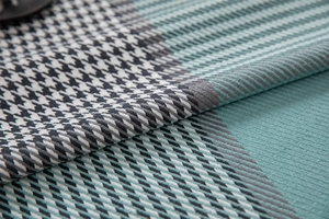 Detailed macro view of woven teal and black houndstooth pattern fabric with fine textures