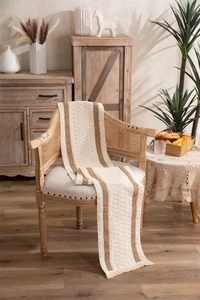 Close-up of woven table runner with brown vertical stripes and tassel details on a chair
