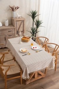 Detail of floral rectangular tablecloth with beige fringe tassels on a wooden table