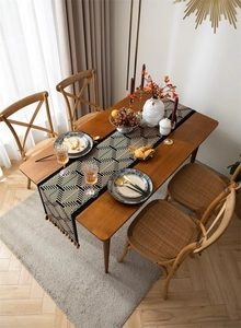 Close-up of jacquard table runner with geometric maze pattern and elegant brown silk tassels