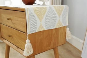 Detail of cotton-linen jacquard runner with yellow leaf patterns and decorative tassels