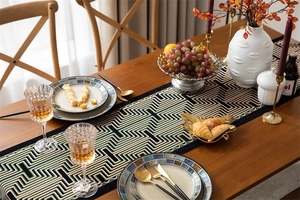 Close-up of geometric jacquard table runner with black and gold patterns and tassels