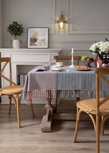 Close-up of houndstooth tablecloth with decorative tassels on a wooden dining table