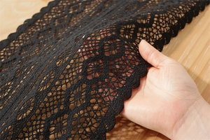 Detailed view of black crochet lace table runner with scalloped edges and diamond mesh pattern