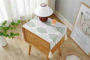 Detailed view of woven leaf pattern fabric with off-white tassels on a bedside cabinet