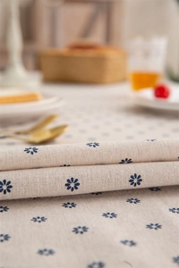 Detailed view of beige cotton linen tablecloth with navy daisy floral print and texture