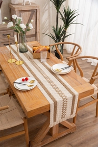 Detail of woven geometric pattern and tassels on linen table runner in rustic style