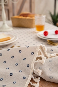 Detailed macro view of beige cotton linen tablecloth with blue floral print and fringe