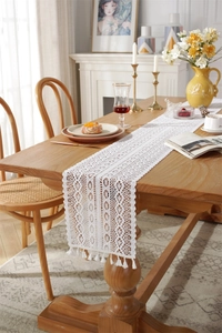 Close-up of white crochet lace table runner with hollow patterns and elegant tassels