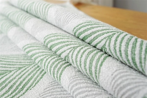 Detail of woven jacquard fabric featuring green and white herringbone texture on a desk