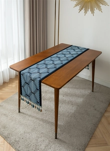 Detail of navy blue geometric jacquard table runner with decorative colorful tassels