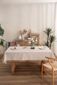 Detailed view of the beige floral tablecloth featuring delicate fringe and cotton texture