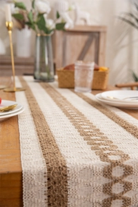 Detail of bohemian cotton linen table runner with woven diamond patterns and tassels
