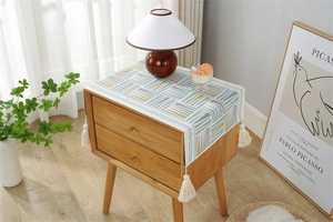 Detail of geometric yarn-dyed woven fabric with ivory tassels for bedside table decor