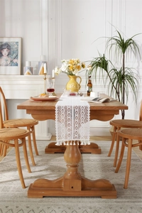 Close-up of white lace table runner with hollow geometric patterns and tassels