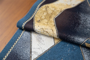 Close-up of geometric jacquard table runner with blue and gold woven metallic threads