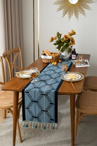 Detail of blue and white geometric jacquard table runner with decorative tassel trim