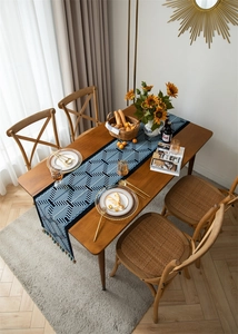 Close-up of navy blue and white geometric jacquard table runner with decorative tassels
