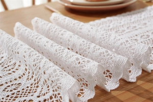 Detailed close-up of white lace table runner with hollow crochet floral patterns