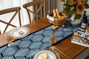 Detail of blue geometric jacquard table runner with woven maze pattern and tassels