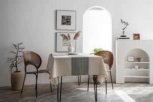 Detail of geometric pattern and fringe tassels on a beige minimalist tablecloth