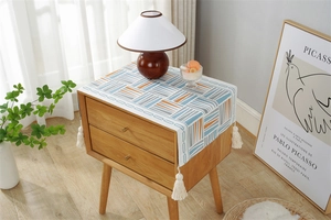 Detail of colorful geometric striped cotton linen cover with tassels on bedside table