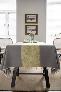 Close-up of damascus jacquard pattern and tassel trim on gray rectangular tablecloth