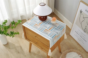 Detail of jacquard dust cover with blue and orange geometric blocks and white fringe tassels
