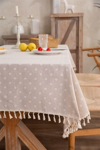 Detail of floral printed tablecloth with beige cotton tassels and fiber texture
