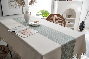Close-up of geometric jacquard pattern and beige tassels on a rectangular tablecloth