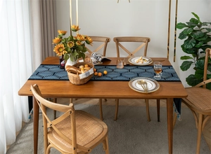 Detailed view of jacquard geometric table runner with blue tassels on wooden table