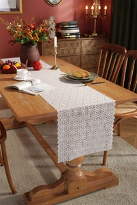 Detailed close-up of white floral lace table runner with intricate hollow-out patterns