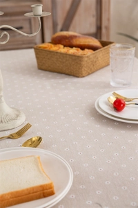 Detail of beige daisy floral tablecloth with tassels and elegant cotton linen texture