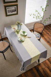 Detail of grey jacquard tablecloth with yellow damask pattern and white fringe trim