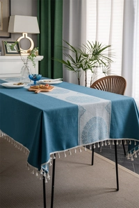 Close-up of blue tablecloth featuring white floral pattern and elegant tassel fringe edge