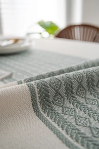 Macro shot of geometric diamond jacquard texture and tassels on beige table runner
