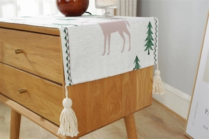 Detail of Christmas reindeer jacquard fabric cover with white tassels on a bedside table
