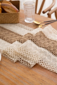 Detail of crochet cotton table runner featuring beige and brown geometric patterns