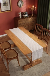 Close-up of white floral lace table runner with hollow design on vintage wooden dining table